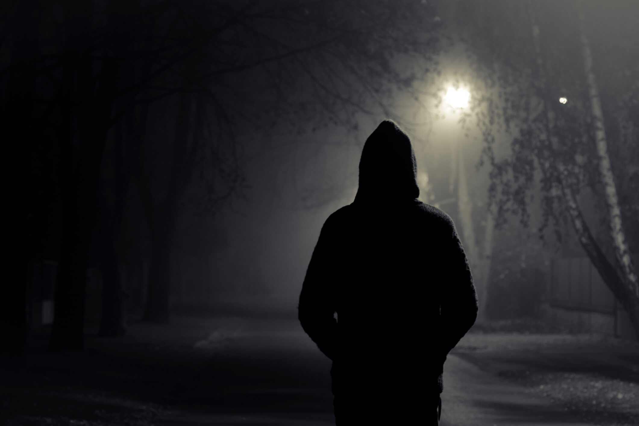 Silhouette of hooded person with spooky dark background Silhouette of hooded person with spooky dark background